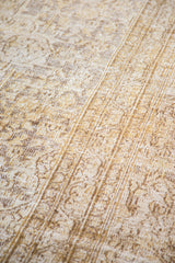 Distressed Khorossan carpet featuring intricate gold and bronze motifs with visible woven texture.