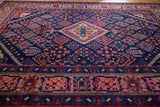 Detail of hand-knotted Joshegan rug's vibrant salmon, indigo border and four-season motifs.