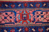Dense hand-knotted Joshegan rug featuring stylized red, indigo, and salmon floral motifs.