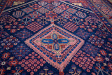 Vintage Joshegan rug detail: central salmon medallion, indigo field, and dense wool with geometric-floral motifs.