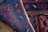 Intricate indigo and salmon jewel-toned patterns on the dense wool pile of a vintage Joshegan rug.