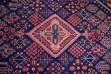 Rich indigo, salmon, and red geometric patterns on a dense Joshegan wool pile.