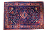 Hand-knotted Vintage Joshegan rug, central salmon medallion, indigo field with jewel-toned seasonal motifs.