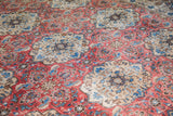 Repeating floral motifs in softened red and light aqua blue on vintage Birjand carpet.