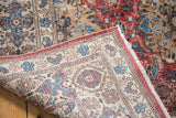 Vintage Birjand carpet's folded corner shows softened red, blue pile, woven back, and fringe.