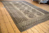 Angled view showcasing the repeating oversized guls and geometric borders on a vintage Afghani rug.