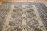 A vintage Afghani carpet's repeating guls shown from a low, angled perspective.