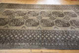 Corner view of a hand-knotted Afghani carpet with oversize guls and a detailed geometric border.