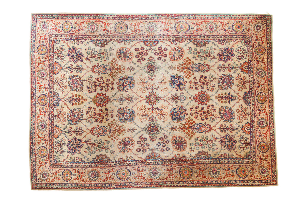 Distressed Kazvin carpet with Safavid palmettes and floral vines in ruby, emerald, navy, and beige.