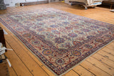 Distressed Kazvin carpet featuring intricate floral bouquets and scrolling vines on a soft beige field.