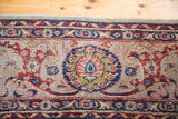Distressed Kazvin carpet detail with central blue palmette and scrolling ruby vines.