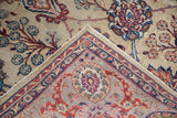 Detail of Distressed Kazvin carpet's folded corner, intricate ruby and navy arabesque border.