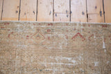 Vintage Malayer rug edge with distressed pile, showing faded geometric patterns and sandy tones.