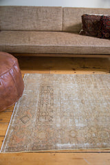 Distressed vintage Malayer rug corner showing sandy bronze tones and faded traditional patterns.