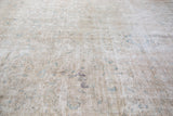 Distressed beige Tabriz rug pile, revealing intricate worn patterns and soft blue hues.