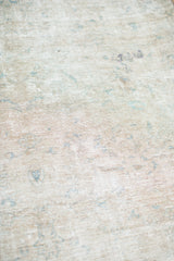 Angled close-up of the blanched, worn texture and intricate weave of the Tabriz rug.