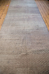 Distressed harlequin pattern detail of a vintage Oushak runner with neutral grey and beige striations.