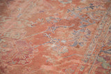 Distressed Oushak carpet, low pile texture, with faded rose, blue, and gray motifs.