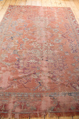 Worn fringe and distressed rose-hued pile of a vintage hand-knotted Oushak carpet.