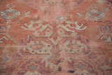 Distressed Oushak carpet pile with faded rose, soft beige motif, and hand-knotted texture.