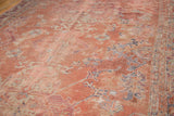 Distressed Oushak carpet with faded rose field, blue and grey stylized motifs.