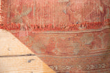 Detail of distressed Oushak carpet's hand-knotted foundation and frayed rose fringe.