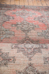 Distressed Oushak runner with worn pile, showcasing rose grapefruit and gray geometric motifs.