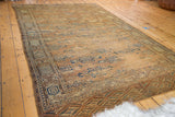 Distressed antique Turkmen Yomud carpet showcasing faded geometric guls and exposed foundation.