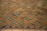 Geometric gul motifs in earth tones and teal, revealing exposed foundation and fringe.