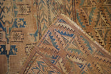 Antique Yomud carpet showing visible foundation, distressed tribal motifs in muted blue and brown.