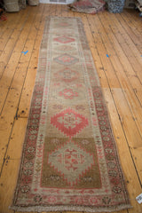 Vintage Oushak runner: muted pink and beige tribal pattern, with detailed side border.