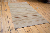 New kilim rug with horizontal bands of ivory, bronze earth tones, and a frayed edge.