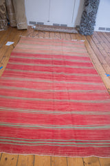 Vibrant cinnabar red and pale rose horizontal stripes on a Moroccan Kilim carpet.