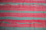 Hand woven texture and striated reddish-pink and aqua bands of a Moroccan Kilim.