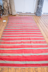 Hand-woven vintage Kilim with prominent striated bands of saturated red and pale green.