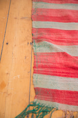 Vintage Moroccan Kilim with handwoven red and muted striated bands, showing green fringe.