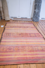 Vintage Kilim carpet with striated bands, geometric triangle motifs, and soft mauve, tangerine, seafoam hues.