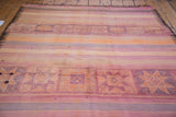 Kilim carpet decorative band featuring geometric triangle-on-triangle and star motifs. Faded orange, mauve hues.