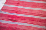 Handwoven texture of the vintage Moroccan Kilim carpet with red, ivory, and mauve stripes.