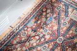 Faded copper field with intricate floral and vine motifs, aqua blue, and navy lattice pattern.