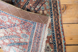 Vintage Bidjar rug mat folded, showing edge binding, fringe, and intricate floral pattern.