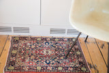 Vintage Sarouk rug detail with dark blue field, softened cherry red, and scalloped floral motifs.