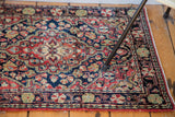 Vintage Sarouk rug's scalloped floral motifs in dark blue, cherry red, and lime green.