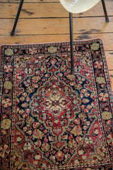 Angled view of Persian Sarouk rug, quatrefoil medallion with red, blue, and green florals.