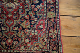 Detailed corner of vintage Sarouk rug, dark blue field, softened cherry red, scalloped florals.