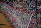 Vintage Sarouk rug folded, exposing its hand-knotted foundation and detailed red, blue border.