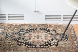 Vintage Sarouk rug's blush scalloped medallion contrasting with the deep navy field.