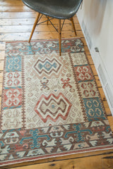 Faded aqua, cochineal red, and beige geometric double medallion on the vintage Kilim mat.