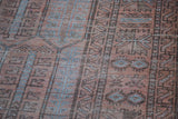 Distressed Belouch carpet pile with geometric arrow and cartouche patterns in copper, blue, charcoal.