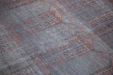 Faded copper orange, grey, and charcoal cartouche motifs on distressed Belouch pile.